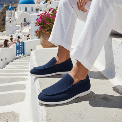 Person wearing navy loafers with a scenic background of white buildings and blue domes.