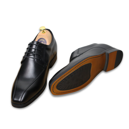 Black leather dress shoes with brown soles on a white background